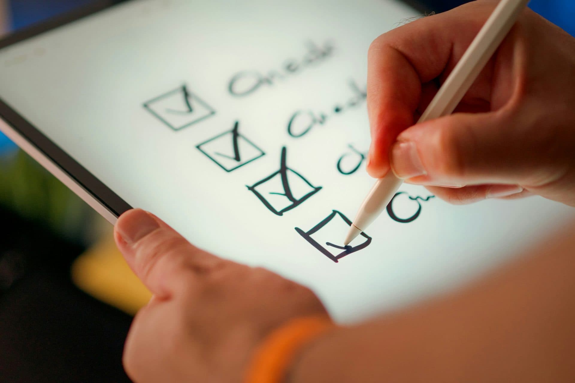 A hand using a stylus to check items on a tablet